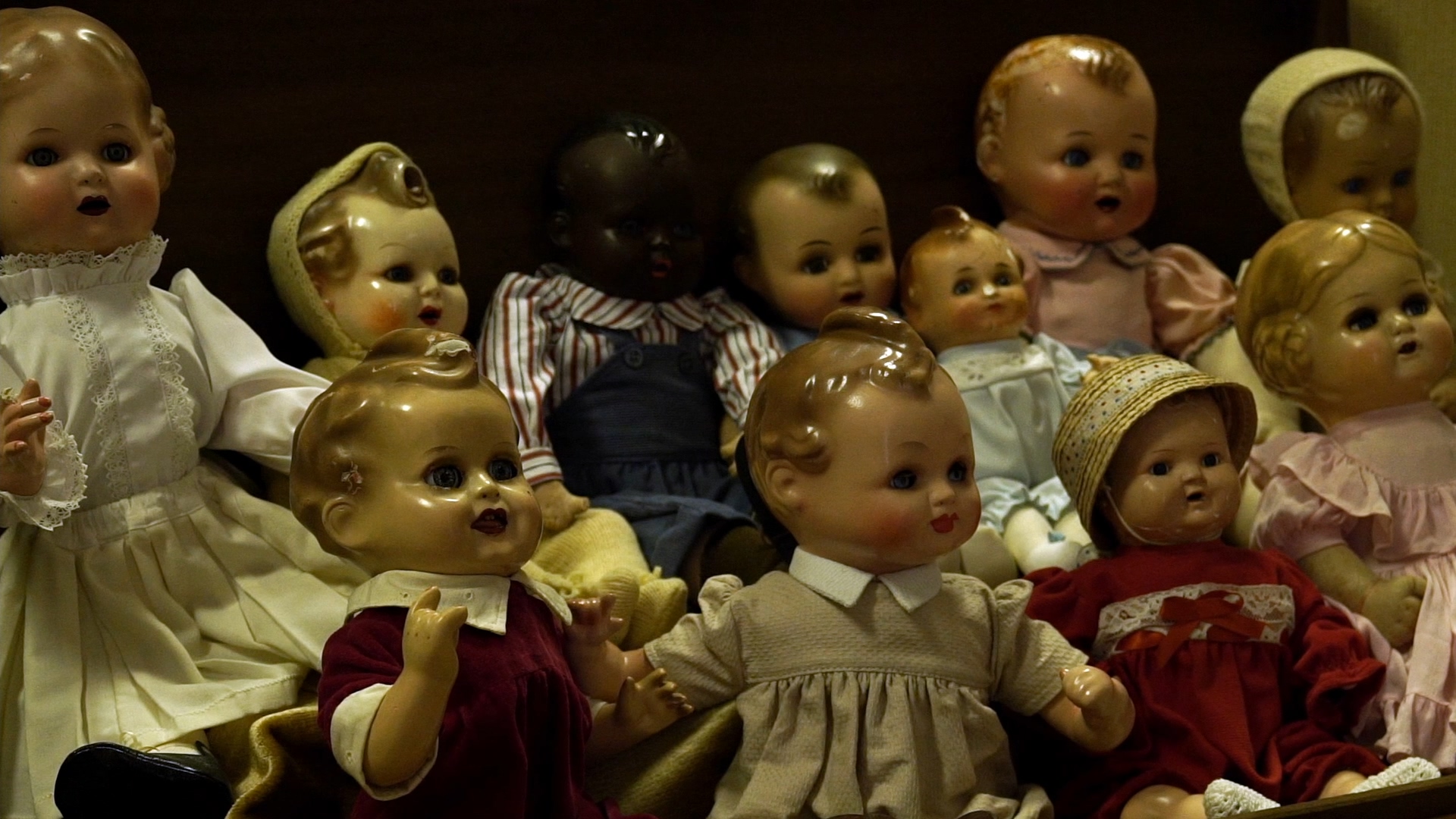 Still de Casa de Bonecas com bonecas alinhadas em uma vitrine.